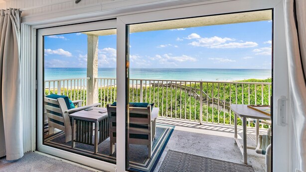 Un balcon avec vue sur l’océan, une table et des chaises.