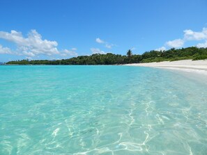 A beach with clear turquoise water, white sand, and a forested hill in the background. - Updated: Luxury Villa, Amazing Views with Pool + Generator (Nazareth)