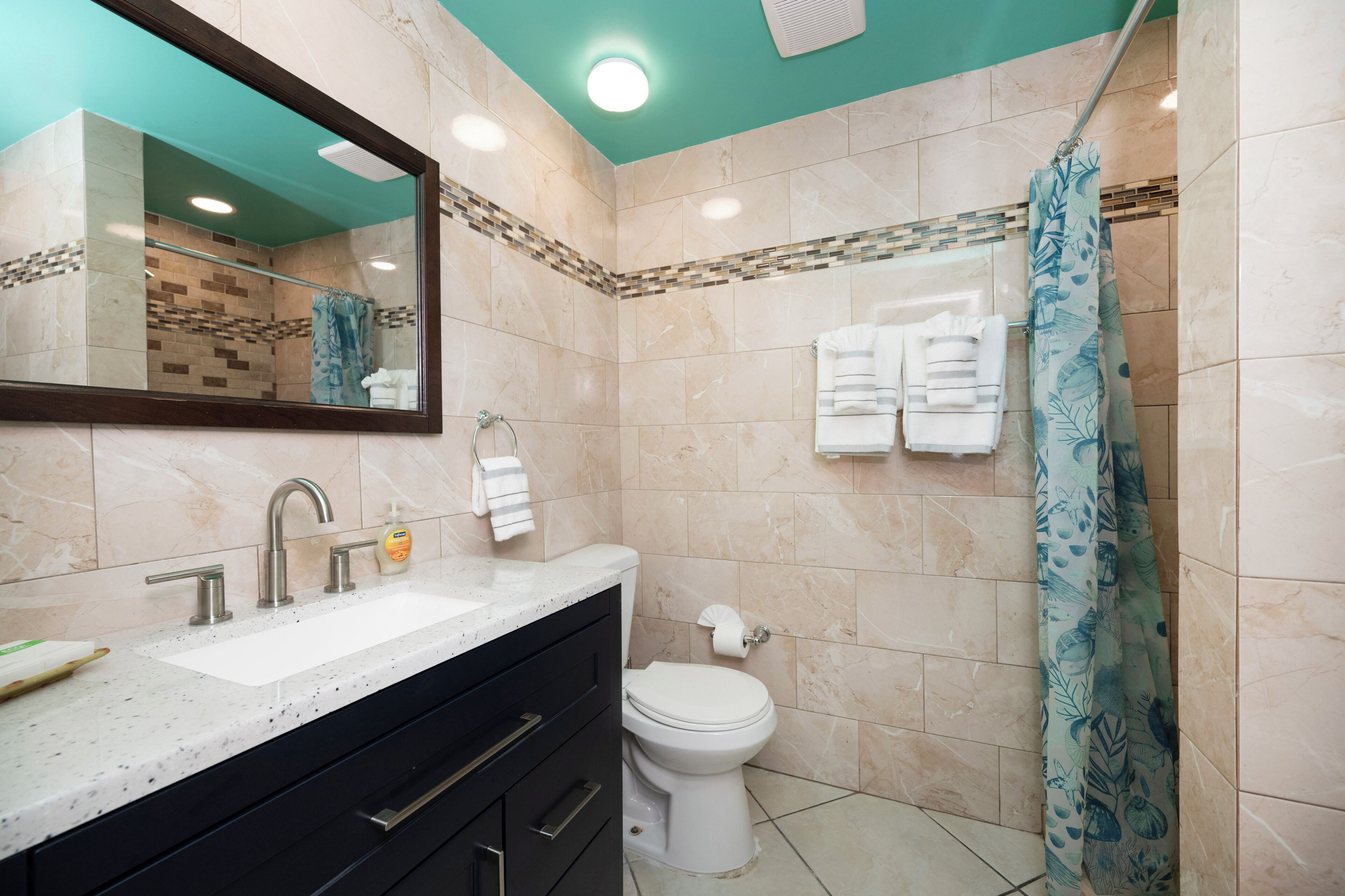 Une salle de bain équipée d’un lavabo, d’un miroir, de toilettes et d’un rideau de douche.