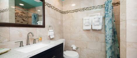 Une salle de bain équipée d’un lavabo, d’un miroir, de toilettes et d’un rideau de douche.
