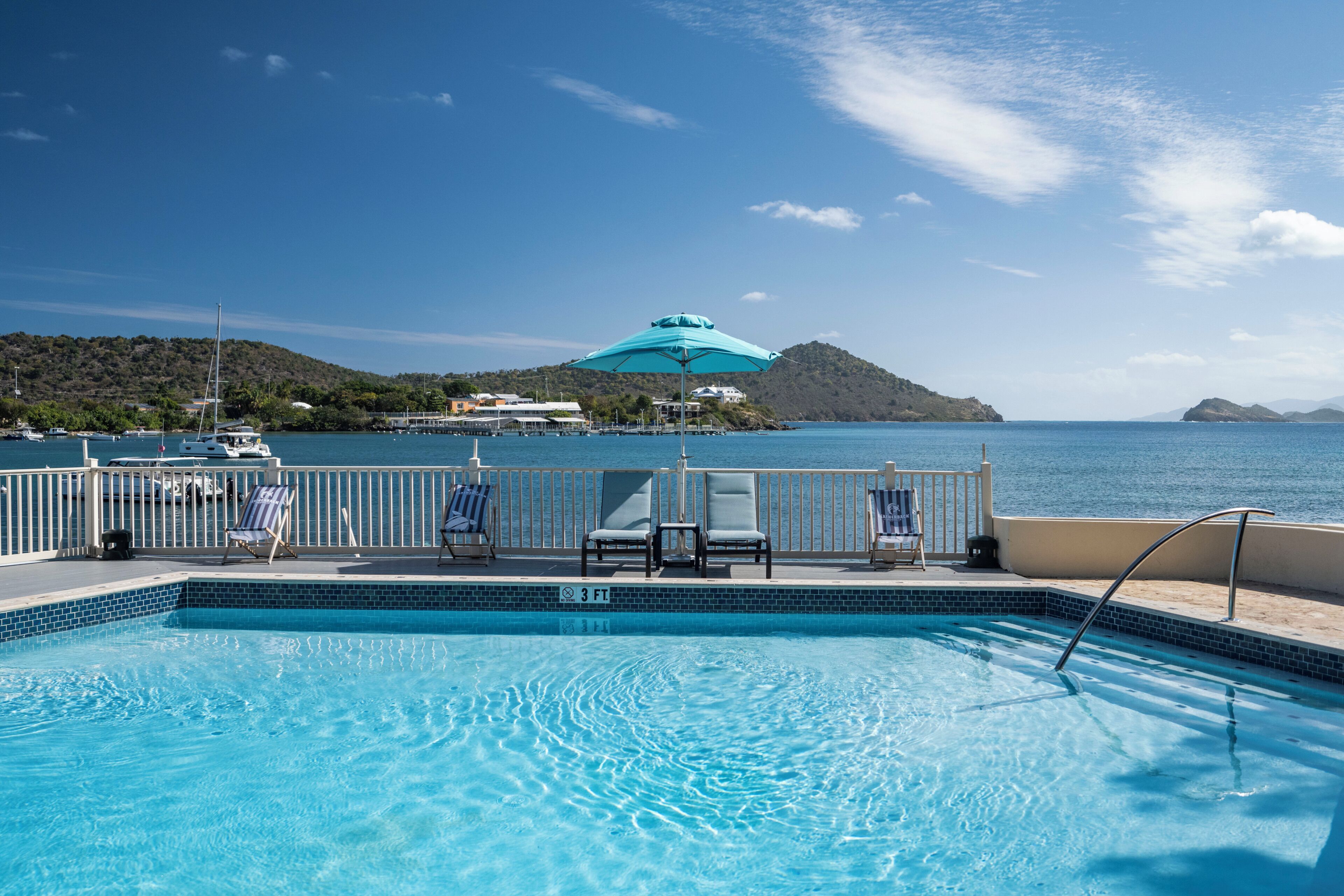 Una piscina con vista al mar y una isla distante.