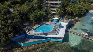 Vista aérea de un resort con una piscina grande, un muelle y una playa.