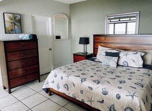 Une chambre à coucher comprenant un lit, une commode, une table de chevet, une lampe et un miroir.