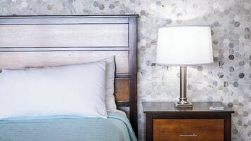 A bedroom with a bed, a nightstand, and a wall with hexagonal tiles.