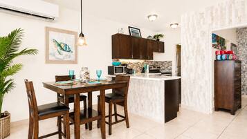 A modern kitchen with dark wooden cabinets, a central island, and a dining area with a table and chairs.