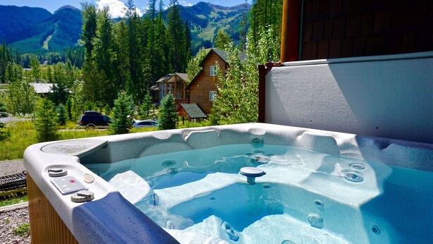 Ein Whirlpool mit Blick auf eine Berglandschaft und eine Holzhütte.