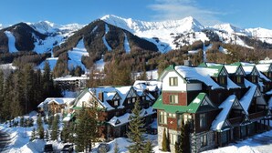 Ein schneebedecktes Bergresort mit Chalets, einer Seilbahn und freiem Blick auf die umliegenden Berge.
