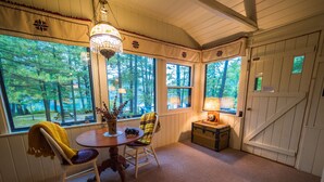 A cozy room with a round table, two chairs, a lamp, a plant, and a chest of drawers. - Quiet and Peaceful 3 Bedroom Family Cottage on Lake George, 12 Miles to TC (Traverse City)