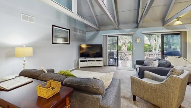 A modern living room with a flat-screen TV, comfortable seating, and a large window offering a view of the outdoors. - Inviting Palmetto Dunes condo w/ pool, private W/D & deck near beach & golf (Hilton Head Island)