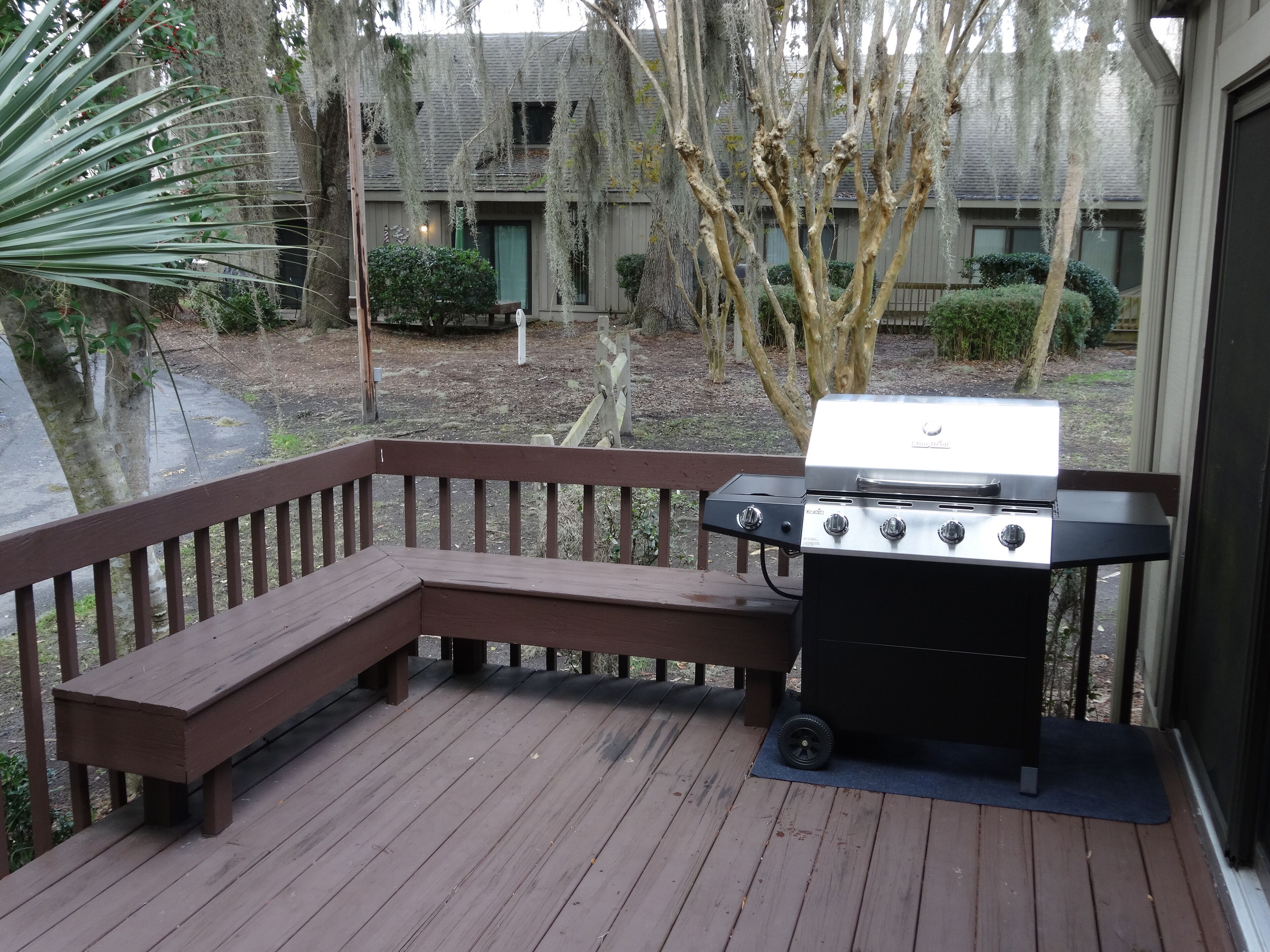 Une terrasse en bois avec un barbecue et un banc.