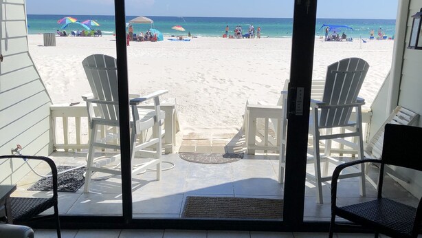 Blick auf einen Strand vom Zimmer aus, mit weißen Stühlen und Fliesenboden.