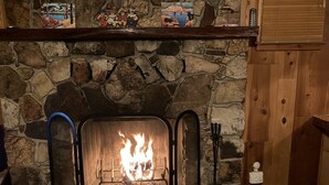 Una chimenea de piedra con fuego, una repisa de madera con adornos y una pared de piedra.