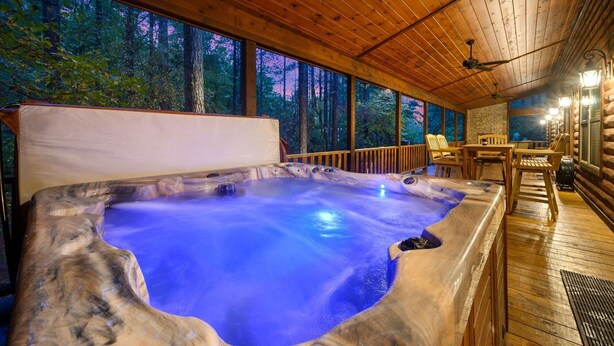 A hot tub in a wooden cabin with a view of the forest.