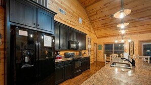 A modern kitchen with dark cabinetry, granite countertops, a built-in oven, and a water dispenser.