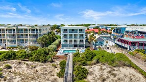 Hotel aan het strand met meerdere gebouwen, een zwembad en een houten looppad.