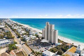 A coastal residential area with a prominent high-rise building, a beachfront, and a parking lot. - An Updated Stunner With Beach Views & Privacy (Seagrove Beach)