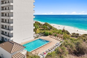 A hotel with a rooftop pool, a beach view, and a white building facade.