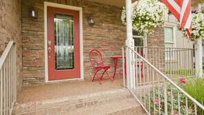 A brick house with a red door, a small porch with a red chair and table, and a white fence. - Riverfront, Kayaks, Boat Dock, Games, Pool, Hot Tub, 10 Min To Dwntwn Nashville! (Nashville)