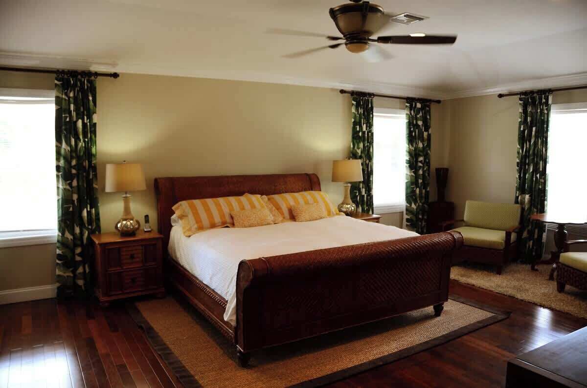 A bedroom with a large bed, two bedside tables with lamps, a ceiling fan, and a chair.