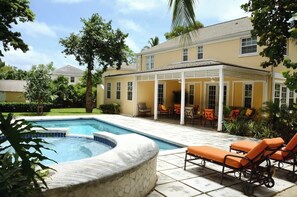 Une piscine avec des chaises longues, un patio couvert et une maison en arrière-plan.