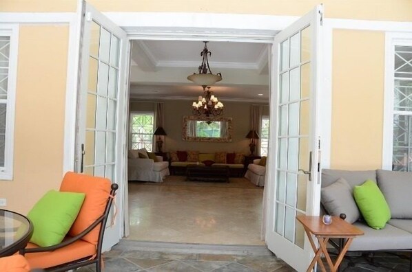 An open doorway leading to a living room with a chandelier, sofas, and a coffee table.