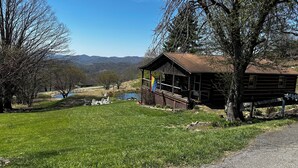 Eine Holzhütte mit Veranda, einer Flagge und Blick auf einen See und Berge.