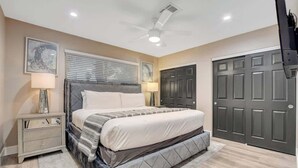 A bedroom with a bed, nightstands, a ceiling fan, and a door. - Close to Strip! Pool,  Spa,  Roulette Table,  Golf (Las Vegas)