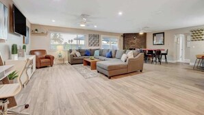 A spacious living room with a sofa set, a dining area, and a TV mounted on the wall. - Close to Strip! Pool,  Spa,  Roulette Table,  Golf (Las Vegas)