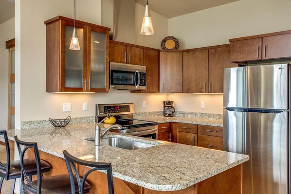 A modern kitchen with granite countertops, stainless steel appliances, and wooden cabinets.