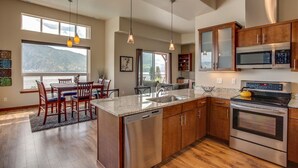 A modern kitchen with stainless steel appliances, a granite countertop, and wooden cabinets.