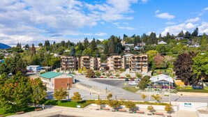A multi-story hotel with a green roof, a parking lot, and a landscaped area with benches.