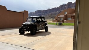A black off-road vehicle parked in a driveway with a mountain backdrop. - 8A6 Amazing Views, Shared Pool/Hot Tub, Private Patio and Garage (MOAB)