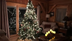 En hyggelig stue med et pyntet juletræ, en behagelig sofa og et bord med en lampe.