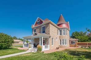 Ein großes, zweistöckiges Haus mit breitem Veranda, einem Türmchen und einem Schornstein.
