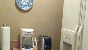 Ett kök med en kaffebryggare, brödrost och kylskåp.