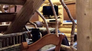 A rustic wooden interior with a slanted ceiling, exposed beams, and a wooden chair. - Cpt Cook - Unique Alaskan log home in trees & wildflowers on 14-acre homestead. (Anchor Point)