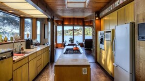Una cocina moderna con armarios de madera, una isla central, un ventanal con vista a un lago y un tragaluz.