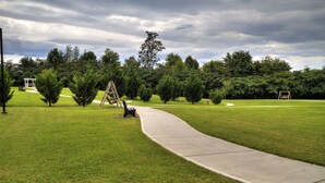 A park with a paved walkway, benches, and a swing set.