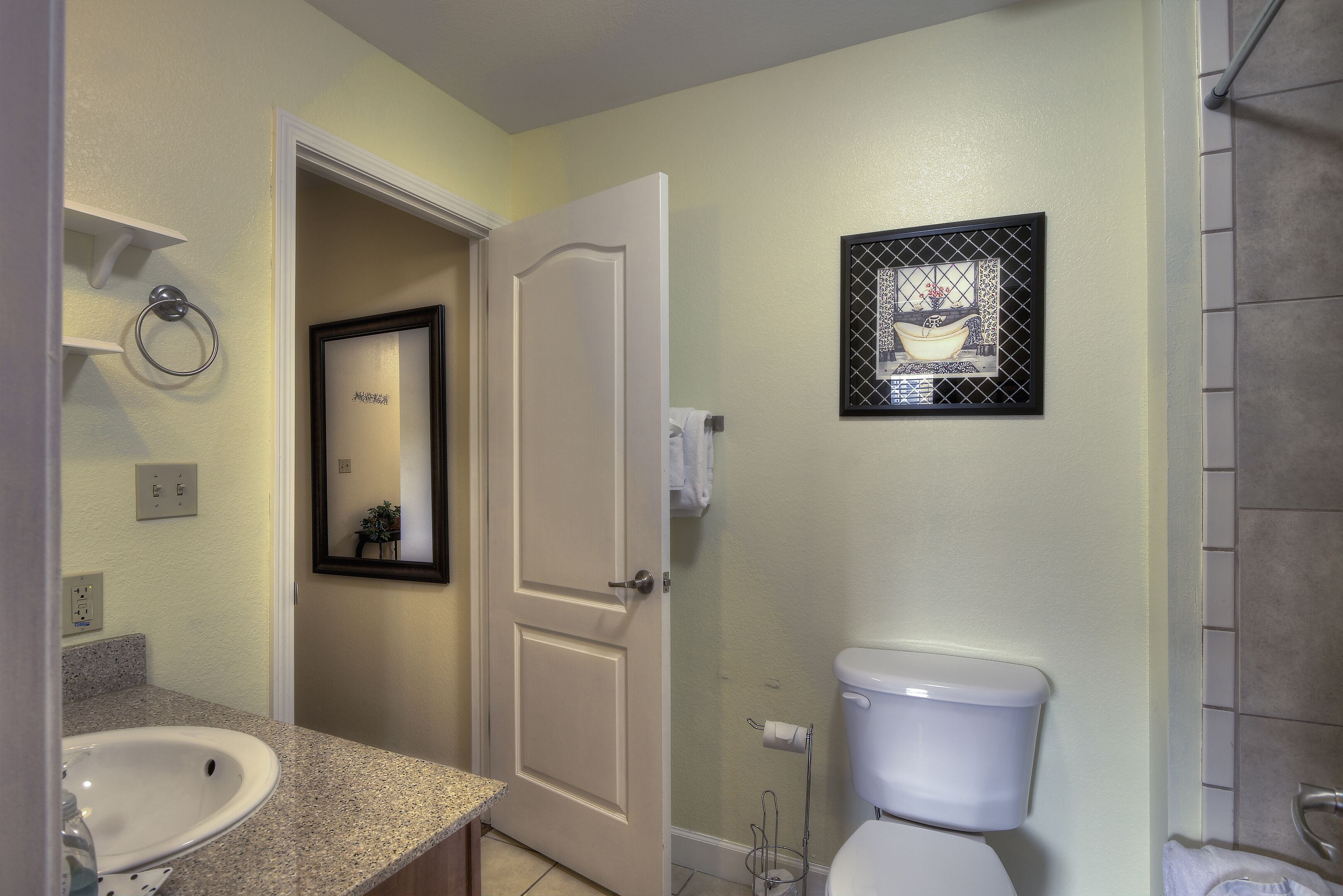 Une salle de bain avec un lavabo blanc, des toilettes et une porte donnant sur une autre pièce.