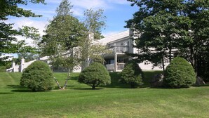 A residential building with a balcony and a well-maintained lawn. - Peaceful, Family Friendly, Heated Outdoor Pool, Awesome Views, Near Story Land (Bartlett)