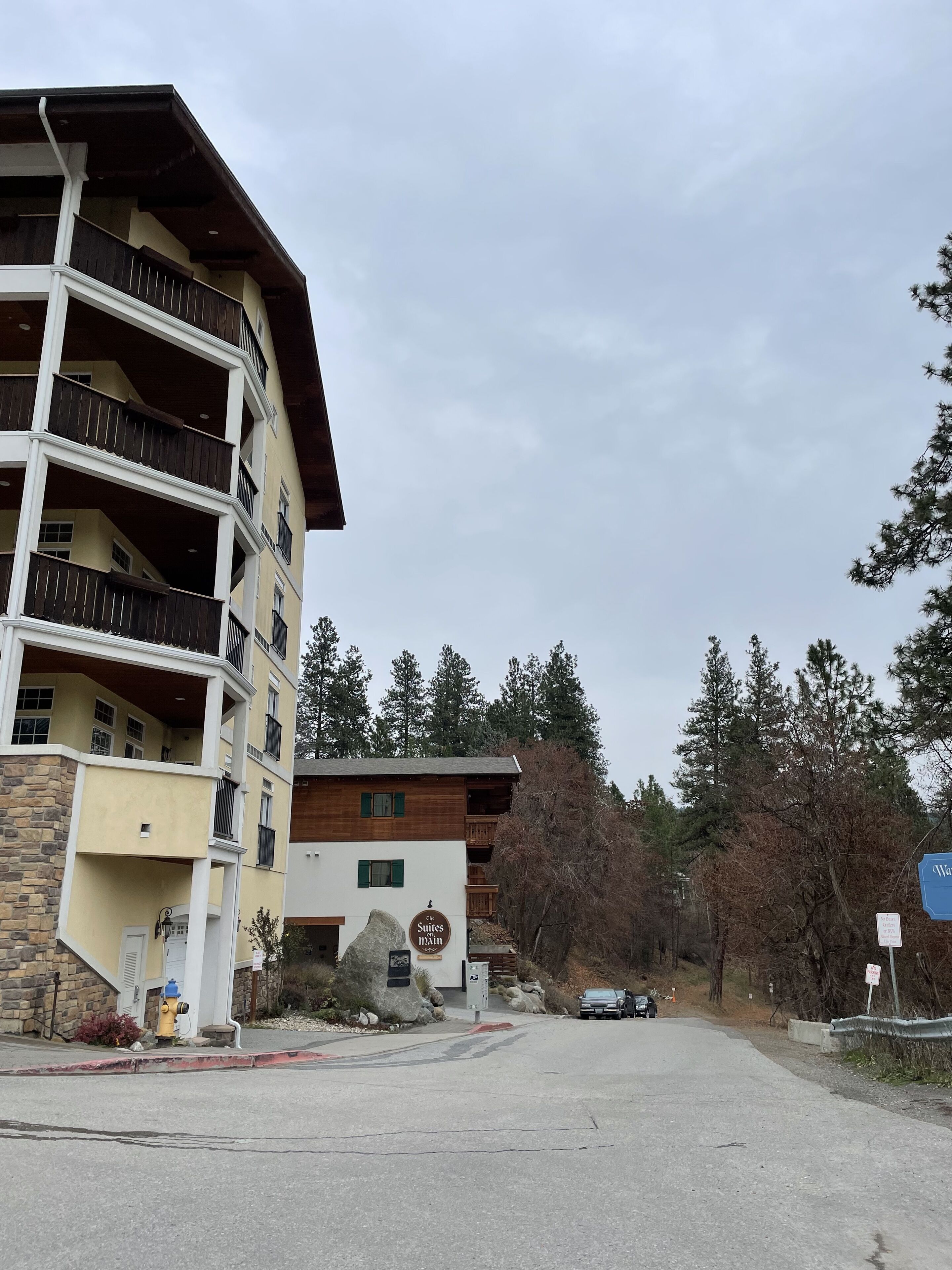 A multi-story building with balconies, a sign for 'The Suites Inn', and a parking area with a yellow fire hydrant.
