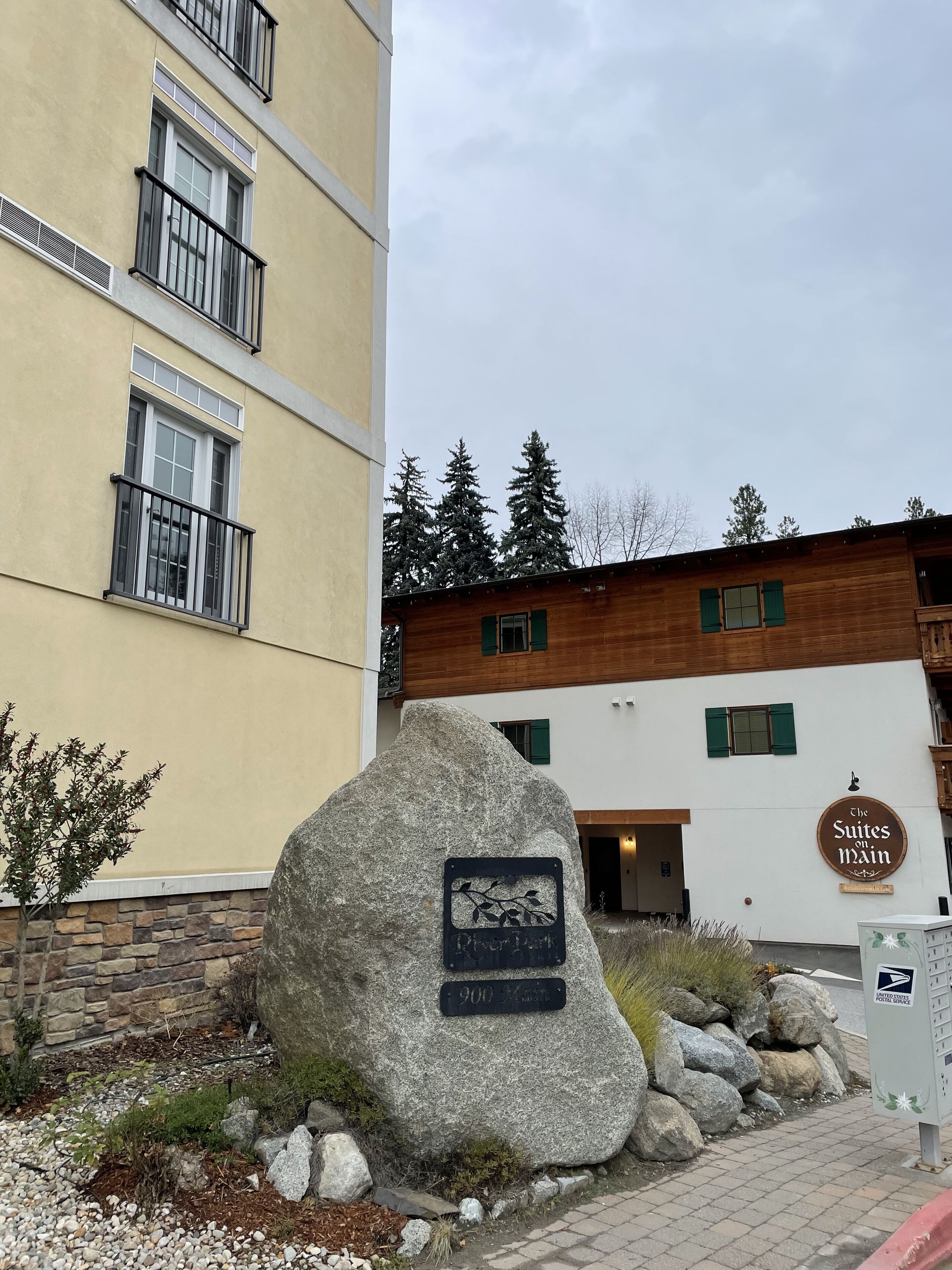 Ein Gebäude mit einer Stein-Fassade und einem Holzaufbau, mit einem Schild, das 'The Suites on Main' anzeigt.