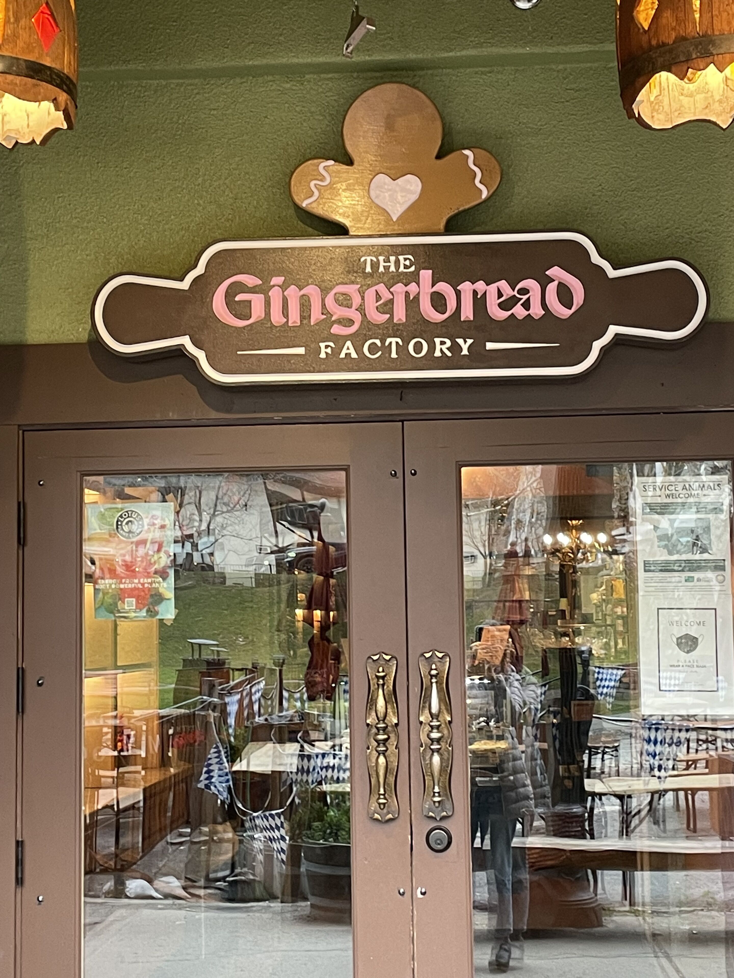 A storefront with a sign reading "The Gingerbread Factory" and a display window showing various items.