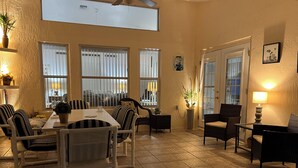 A dining area with a table and chairs, a ceiling fan, and a view of the outside through large windows. - Gorgeous, near parks, 2 master suites, private pool&spa, covered patio, wifi (Davenport)