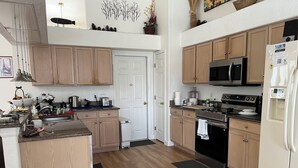 A kitchen with wooden cabinets, a microwave, a stove, and a refrigerator. - Gorgeous, near parks, 2 master suites, private pool&spa, covered patio, wifi (Davenport)