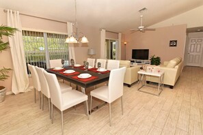Un salon moderne comprenant un coin repas, un canapé, un téléviseur et un ventilateur de plafond.