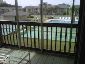 A view from a balcony with a pool and tennis court visible.