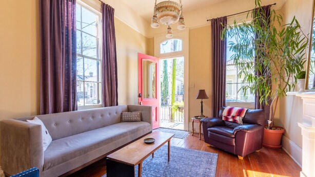 A living room with a sofa, a coffee table, a chair, a potted plant, and a view of the outside.