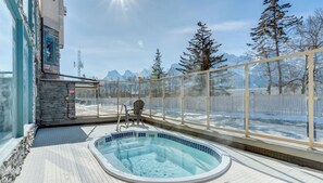 An indoor swimming pool with a glass enclosure, a chair, and a view of snow-covered mountains.