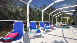 A covered outdoor pool area with blue lounge chairs and a pool.